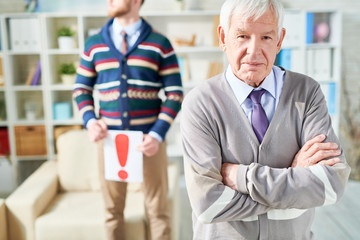Obraz premium Waist up portrait of white haired senior man standing with arms crossed and looking at camera while posing in psychologists office, copy space
