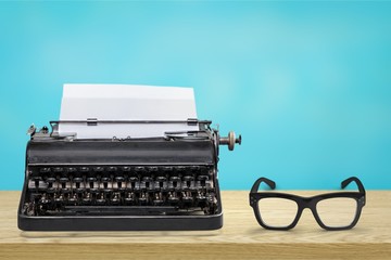 Retro black typewriter and spectacles on wooden