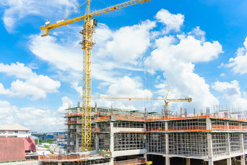 Construction site. Construction cranes and high-rise building under construction against blue sky. © navintar