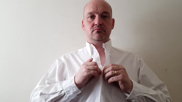 Male with a partially amputated index finger on his right hand buttoning a white shirt.