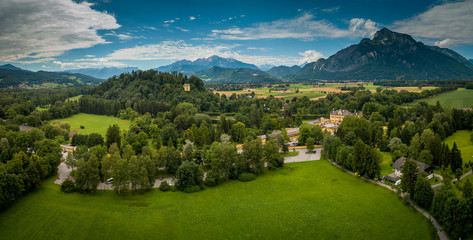 Aerial panorama of yellow Hellbrunn palace castle with scenic garden below the Alps in Salzburg...