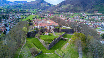 Aerial panorama view of Saint Jean Pied de Port, a fortified military town in the Pyrenees along the el camino de santiago, with blue sky abd lush green pasture. Star shaped Vauban fort.