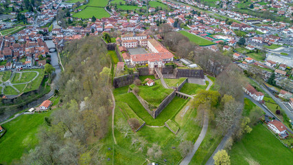 Aerial panorama view of Saint Jean Pied de Port, a fortified military town in the Pyrenees along the el camino de santiago, with blue sky abd lush green pasture. Star shaped Vauban fort.