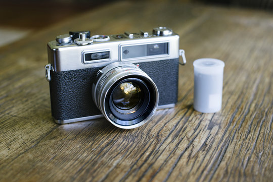 A frontal view of an old rangefinder film camera with a film canister