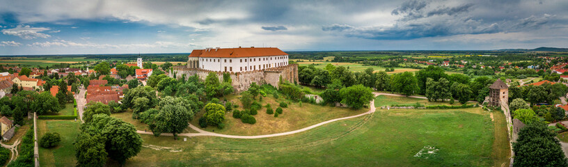 Fototapeta na wymiar Aerial panorama of medieval Siklos castle in Hungary with brick walls, barbican, towers and Gothic chapel and stormy blue sky