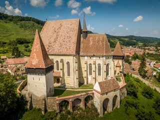Aerial panorama view of Biertan fortified church, seat of the Saxon bishop in Transylvania, with triple ring of walls, towers, matrimony room blue cloudy sky background