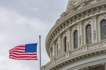 United States Capital building with waving American flag in Washington DC with light blue sky