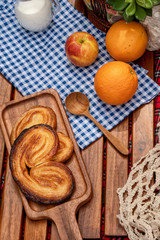 set of food for picnic, butterfly shape danish cookies named Palmiers, or Elephant Ears, or French Heart and fruits with a jar of milk on wooden plank