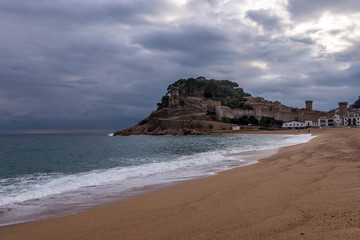 Fototapeta na wymiar Aerial view of popular Costa Brava vacation beach town Tossa de Mar near Barcelona Spain with medieval walls, towers and stormy cloudy sky in the background