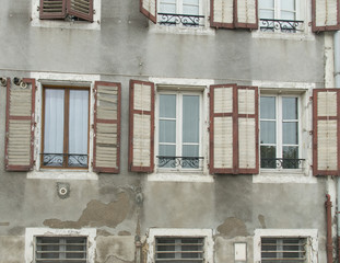 Obraz premium Wall of windows with faded and broken shutters on historic building in Europe