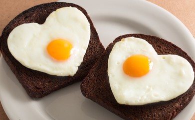Two Slices of Bread with Fried Eggs in the Shape of Heart on the