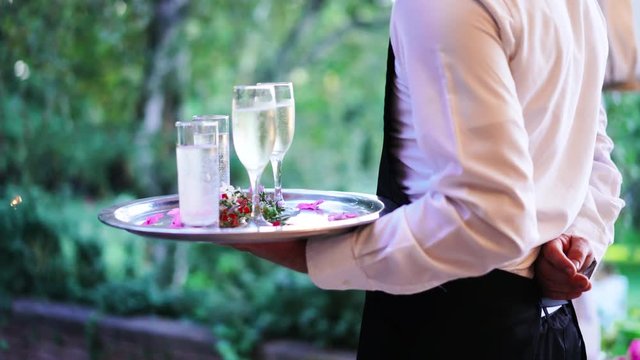 Waiter and champagne glasses on a tray in Luxury Restaurant. Catering service. 4k