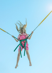 A beautiful girl in a dress with fluttering hair jumps on the attraction. The invigorating ride.