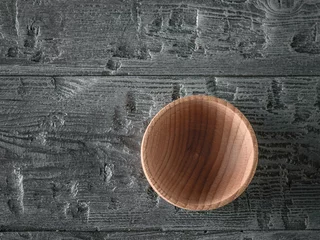 Fotobehang Wooden bowl on the dark wooden table. The view from the top. Flat lay. © kvladimirv