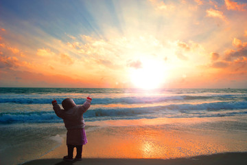 Fototapeta na wymiar Trust concept: Child on the beach looking on the sea sunset