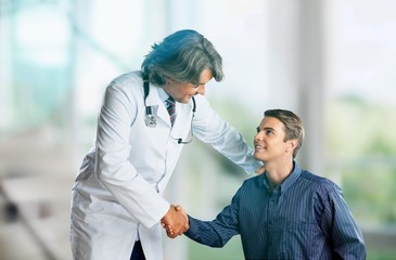 Fototapeta na wymiar Friendly Senior doctor handshaking with young patient