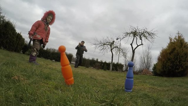 Father throws howler blaster rocket and hits plastic blue bowling pin target. Slow motion