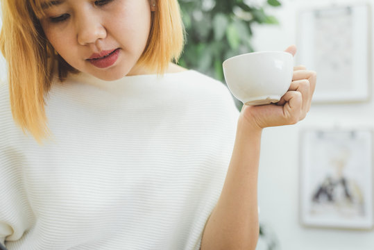Attractive beautiful asian woman enjoying warm coffee in the kitchen at her home. Asian female wearing comfortable sweater holding a cup of coffee. lifestyle asia woman at home concept.