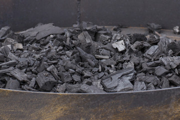 Heap of black charcoal briquettes in place for grilling