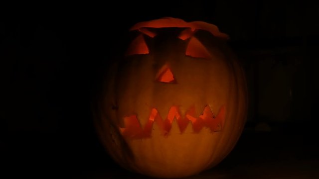 Luminous grimace carved on the Halloween pumpkin to the Day of All Saints in dark