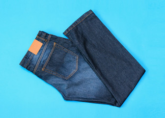 Folded in half men's blue jeans on blue background. The view from the top. Flat lay.