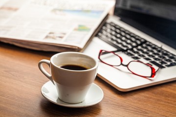 Business Desk with Coffee, Eyeglasses, Laptop and Newspaper