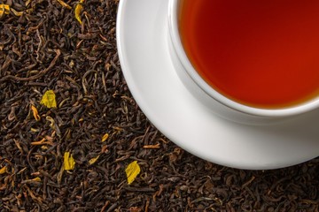 Cup of Tea Standing on Dried Black Tea Leaves