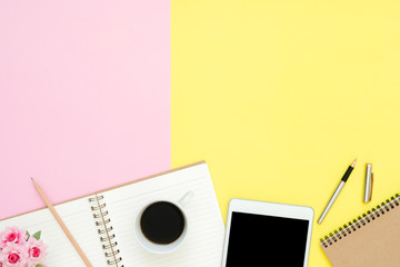 Office desk working space - Flat lay top view photo of working space with blank mock up tablet, coffee cup and notebook on pastel background. Pastel pink yellow color copy space working desk concept.