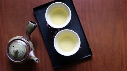Obraz na płótnie Canvas Flat lay of Japanese tea set consists of tea pot, tea cups and a black tray on wooden surface