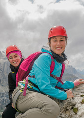 two young attractive female mountain climbers on a steep and exposed Via Ferrata in Alta Badia in...