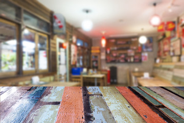 Old multi-colored wooden table in front of abstract blurred bokeh background of restaurant.