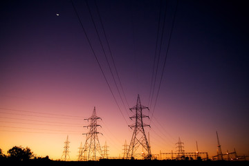 Silhouette High voltage electric towers at sunset time