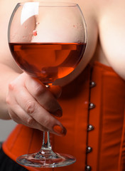 Fototapeta na wymiar Red wine in bra between boobs. wine list for the restaurant menu. Woman in red holding wine glass. Woman Plus Size posing with glass of wine. XXX size.