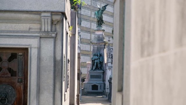 Angel and Three men holding flag mausoleum statue in La Recoleta Cementery at daytime long shot tilt down to high