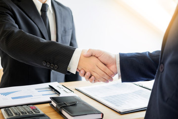 two business men partners shaking hands during a meeting to deal complete to sign agreement contract and become success in the office.