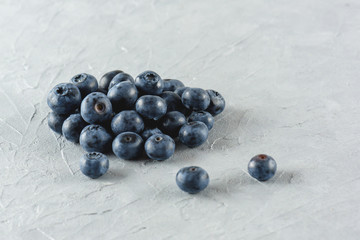 Blueberry on a gray cement background. Ripe and juicy fresh blueberry close-up. A bunch of berries close-up.