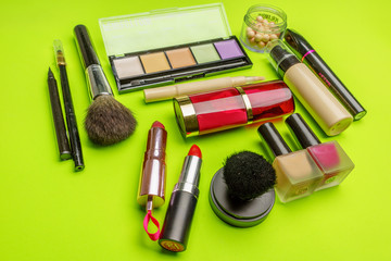 The composition of accessories, makeup cosmetics on a bright green background. Top view.   