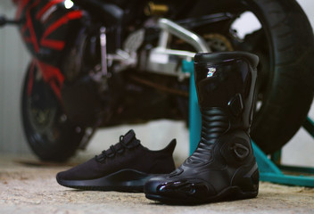 Black motorcycle shoes and black running shoes. Sports equipment