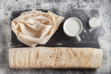Fresh flatbread on black baking surface, top view. Traditional bread in Middle East and Central...