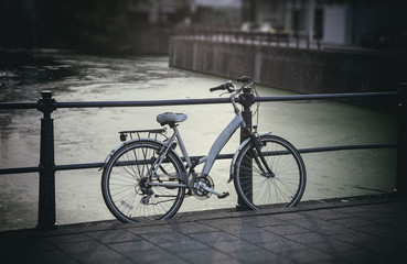 Fototapeta na wymiar Bicycle parked on bridge over city river, blurry background.