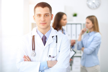 Fototapeta premium Friendly male doctor on the background with patient and physician