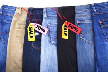 Shop sale of clothes, discounts, jeans different colors blue, green, black on white background isolated close up