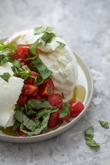 Büffelmozzarella Kugel mit Tomaten, Basilikum, Olivenöl und weißen Balsamico auf Teller