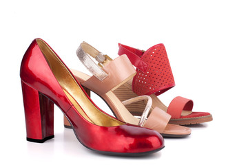 Red, beige and orange female shoes and sandals with high heels for sale side view on white background isolated close up