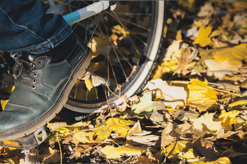 Men foot on pedal bicycle in autumn park