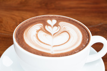 coffee cup latte art on wooden table.hot drink coffee with milk froth for breakfast.heart shape art foam texture top view.