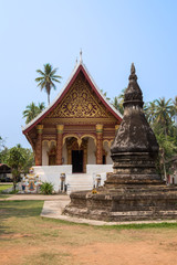 Fototapeta premium Old and aged chedi or stupa in front of the Buddhist Wat Aham Temple in Luang Prabang, Laos, on a sunny day.