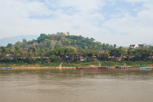 Luang Prabang, Mount Phousi (Phou Si, Phusi, Phu Si) and moored boats on Mekong River in Laos, viewed from the Chomphet District on a sunny day.