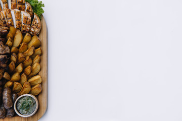 Most meat dish - beef kebabs, sausages, grilled mushrooms, potatoes, tomatoes and sauce. The best choice for a beer. Close-up on a white background.