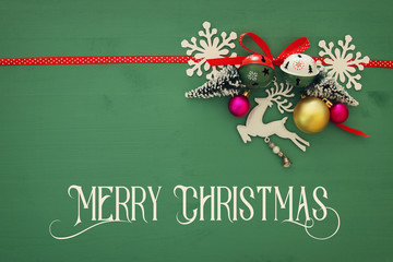Christmas background with red silk traditional ribbon, white deer, evergreen tree and jingle bells.